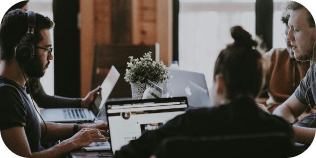 a group of people in an office working on laptops
